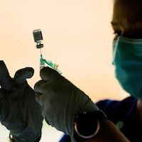 Un employé de la santé tient une seringue et une fiole de vaccin.