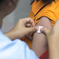 Une personne applique un petit coton à l'endroit de la piqûre du vaccin.