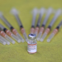 Une fiole de vaccin Pfizer et plusieurs seringues.