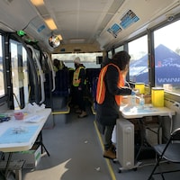 Des personnes dans un autobus aménagé avec des tables de travail.