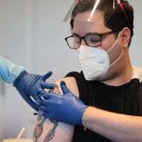 Un homme appuie sur son bras après avoir été vacciné.