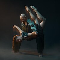 Un danseur tient une danseuse en équilibre, tête à l'envers, dans ses bras.