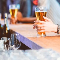 Une femme tient un verre de bière à un bar.