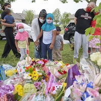 Une mère et ses deux filles sont devant le monument de fleurs commémorant les victimes.
