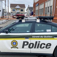 Une voiture de la Sûreté du Québec et un ruban orange dans la rue. 