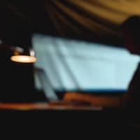 Un homme travaille dans l'ombre sur un ordinateur.