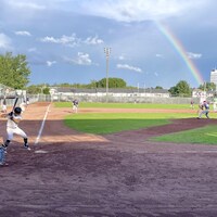 Un match de baseball avec un arc-en-ciel comme fond.