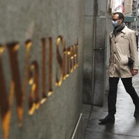 Un homme qui porte un masque de protection médicale entre dans l'édifice de la Bourse de New York.