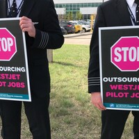 Des personnes qui tiennent une pancarte dans leurs mains sur laquelle il est écrit: Stop, outsourcing westjet pilot jobs