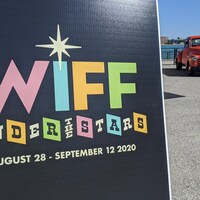 Une pancarte annonçant le nouveau festival avec une voiture en second plan.
