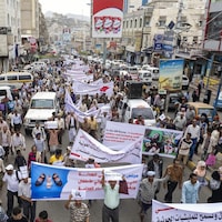Une foule de gens manifeste tenant des banderoles blanches.