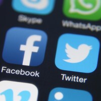 Les icones des applications YouTube, Facebook et Twitter sur l'écran d'un téléphone mobile. 