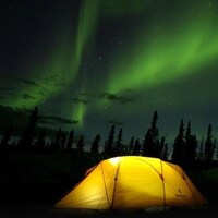 Des aurores boréales au-dessus d'une tente.