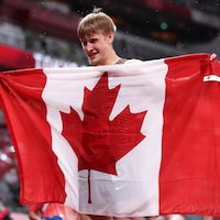 Zachary Gingras est heureux en tenant un drapeau canadien.