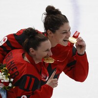 Deux hockeyeuses de profil croquant dans leurs médailles d'or.