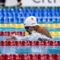 Katarina Roxon nage dans la piscine olympique de Tokyo entre deux couloirs.