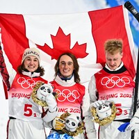 Marion Thénault, Miha Fontaine et Lewis Irving soulève le drapeau du Canada.