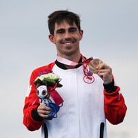 Stefan Daniel sur le podium, tout sourire, médaille de bronze à la main.