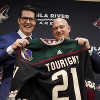 Les deux hommes sourient et tiennent un chandail des Coyotes au nom de Tourigny.