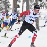Un fondeur canadien pousse dans une montée devant un groupe de quatre skieurs.