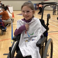 jeune fille assise dans un fauteuil roulant avec un chandail blanc devant elle