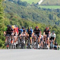 Un groupe de cyclistes grimpent une route au Québec.