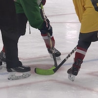 Deux joueurs de hockey attendent que l'arbitre dépose la rondelle sur la patinoire