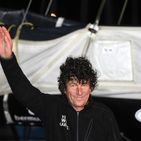 Jean Le Cam, participant au Vendée Globe, salue la foule sur le pont de son bateau. 