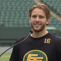 Jordan Beaulieu devant un lutrin avec un chandail des Elks.