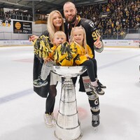 La famille pose sur la patinoire avec un immense trophée