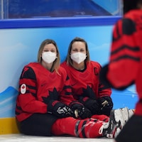 Deux hockeyeuses assises sur la glace prennent la pose après la victoire.