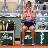 Une joueuse de tennis, vêtue de noir, cache ses yeux avec une serviette rose lors d'une pause pendant un match à Roland-Garros.