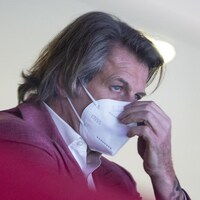 Le directeur général du Canadien, masqué, observe l'action sur la glace.