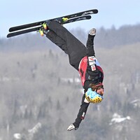 Un skieur effectue une manœuvre dans les airs lors de son saut.