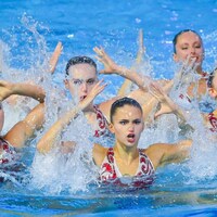 Les nageuses en action bras au-dessus de la tête, toutes en position identique.