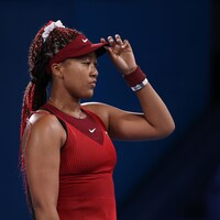 Une joueuse en rouge tient sa casquette.