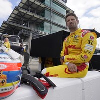 Romain Grosjean, appuyé sur un mur de la piste d'Indianapolis, est vêtu de sa combinaison de l'écurie Andretti Autosport.