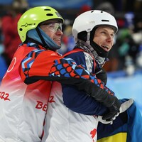 Deux skieurs acrobatiques se serrent dans leurs bras après leur descente.