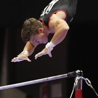 Le gymnaste William Émard s'apprête à agripper une barre horizontale.