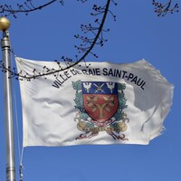 Le drapeau de la Ville de Baie-Saint-Paul sur un ciel bleu d'hiver.