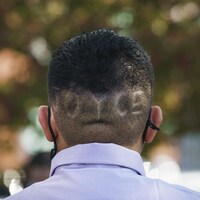 Un homme de dos, avec le mot JOYCE inscrit au rasoir dans la chevelure.