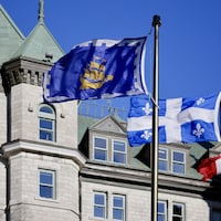 La façade de l'hôtel de ville de Québec, derrière les drapeaux de la ville, du Québec et du Canada