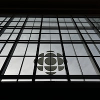 Le logo de Radio-Canada au bas d'une grande façade en verre.