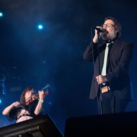 Karl Tremblay ferme les yeux en chantant sur la scène extérieure. Marie-Annick Lépine l'accompagne au violon.