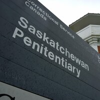 En avant-plan, on y voit un panneau sur lequel est écrit Pénitencier de la Saskatchewan. Derrière, on y voit une tour du pénitencier. 