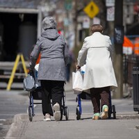 Deux femmes poussent des déambulateurs dans la rue.