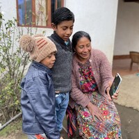 Deux enfants, ainsi que leur mère, parlent à leur père par vidéoconférence.