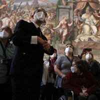 Plusieurs personnes regardent les fresques murales d'un musée au Vatican.