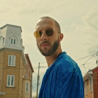 Le rappeur Eman pose dans une rue avec ses lunettes de soleil.