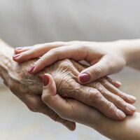 Une femme jeune tient la main d'une femme âgée.